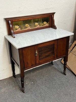 une armoire en bois avec un plateau en marbre, à côté d'une pile de cartons