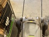 une tondeuse à gazon posée à côté d'un caddie