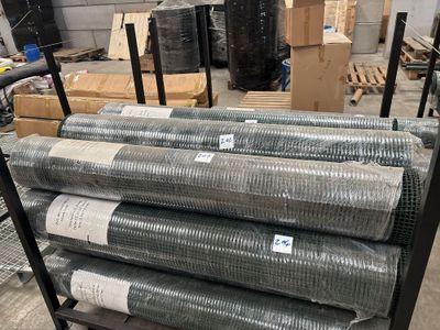 de nombreux rouleaux de treillis métallique sur un chariot dans un entrepôt