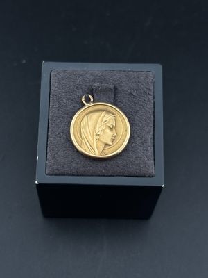 une petite médaille en or sur laquelle est représenté le visage d'une femme