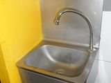 a stainless steel sink in the corner of a bathroom