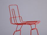 une chaise en métal rouge posée sur un sol blanc
