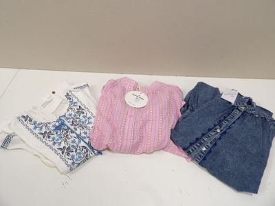 trois paires de jeans et un pull posés sur une table