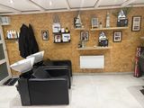 a picture of a hair salon with black chairs and pictures on the wall