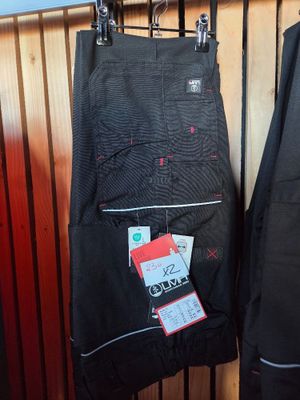 two pairs of pants hanging on a rack in front of a wooden wall
