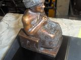 une statue en bronze représentant une femme assise sur une caisse