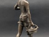 bronze statue of a boy with a basket on a rock