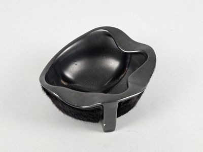 a black bowl with a black handle on a white surface