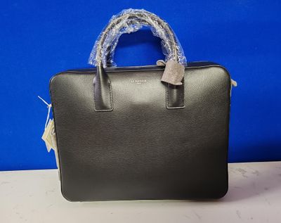 un sac à main noir avec une poignée bleue posé sur une table blanche