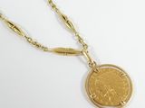 a close up of a gold coin on a chain on a white surface