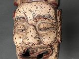 an image of a wooden mask on a table with a gray background