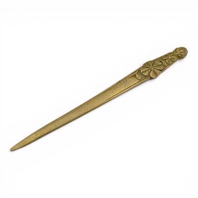 a gold colored metal spoon with a flower design on it
