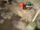 some buckets are sitting on a wooden bench in a dirty room