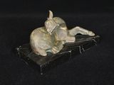 une statue représentant un chat allongé sur une surface noire