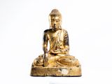une statue en or représentant une personne assise sur un rocher