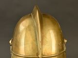 brass helmet on a stand against a black background