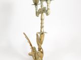 a tall brass candle holder with a bird on it