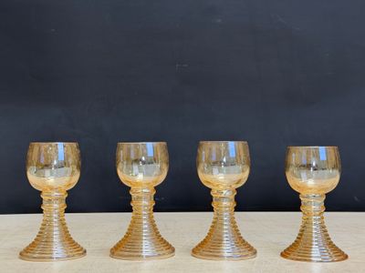 four gold glass goblets sitting on a table with a black background