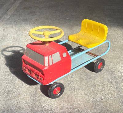 a red toy truck with a yellow seat and steering wheel