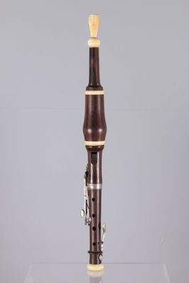 a close up of a clarinet on a clear surface with a gray background