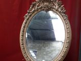 a mirror sitting on a wooden stand in front of a red curtain