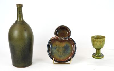 three vases and a bottle on a white surface
