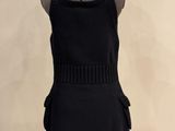a black dress on a mannequin stand with a white background