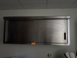 une armoire à pharmacie en acier inoxydable située au-dessus d'un évier dans une cuisine