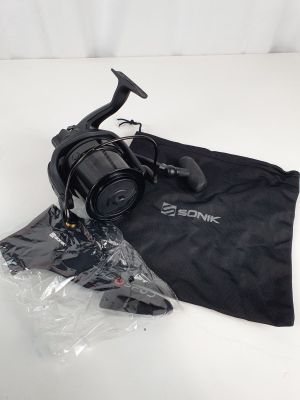 un gros plan sur un moulinet de pêche et un sac posés sur une table