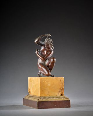 une statue en bronze représentant une femme assise sur un bloc de marbre