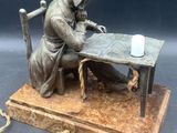 a statue of a man sitting at a table with a candle