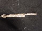 an old silver knife with a metal handle on a black surface