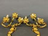 a pair of gold plated sconces with flowers and leaves