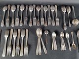 un grand nombre de cuillères et de fourchettes en argent disposées sur une table