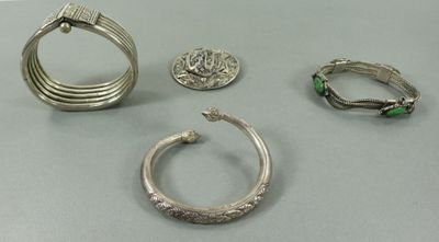 trois bagues en argent et une bague sertie de pierres vertes posées sur une table