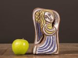 a ceramic figurine of a woman and an apple on a table