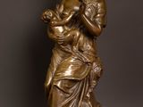 a bronze statue of a woman holding a child on a wooden table