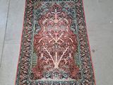 un tapis oriental posé au sol, orné d'un motif représentant l'arbre de vie