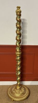 brass plated candle holder on a carpeted floor in front of a red wall