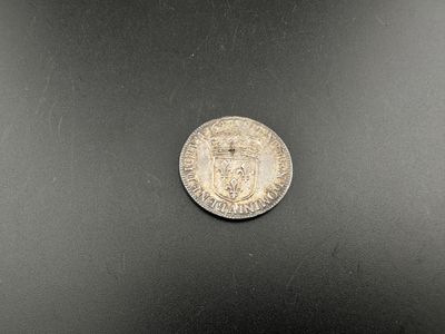 une pièce d'argent posée sur une surface noire, avec un fond blanc