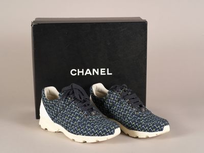 une paire de baskets bleues et blanches devant une boîte noire