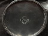a silver plate with a silver lid on a black surface
