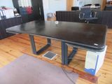 une table noire sur laquelle est posé un ordinateur portable, dans un bureau