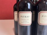 three bottles of red wine are lined up on a table