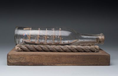 a ship in a glass bottle on a wooden base