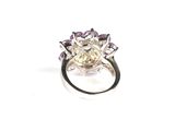 a close up of a diamond and amethorate ring on a white surface