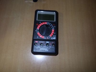 un multimètre numérique posé sur une table à côté d'un téléphone portable