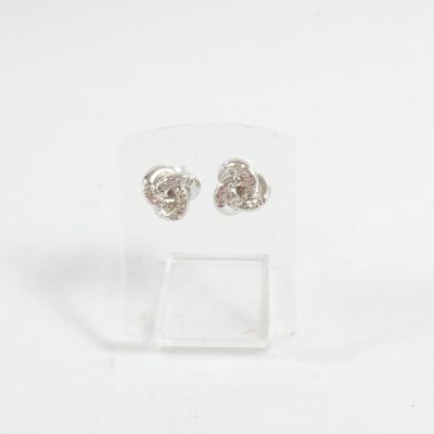 une paire de boucles d'oreilles en argent posée sur un présentoir transparent