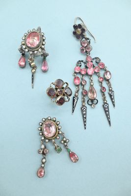 two pairs of earrings and a broochet on a blue surface