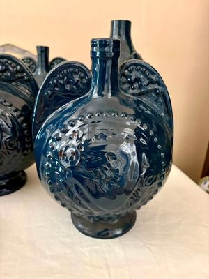 trois vases bleus posés les uns à côté des autres sur une table